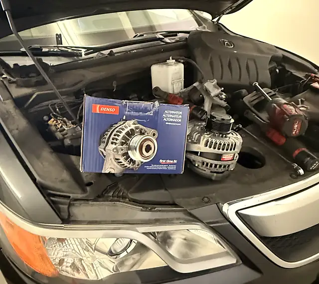 New Denso alternator ready to install in an Acura engine bay during a mobile alternator repair