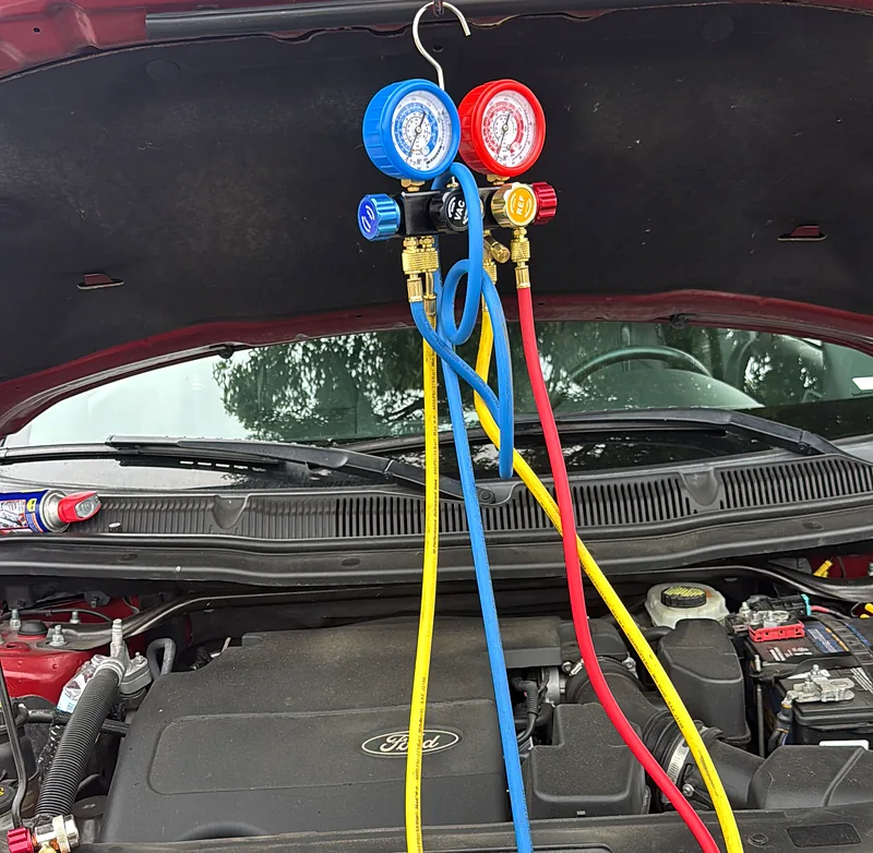 A/C manifold gauges hooked up to a Ford SUV during mobile A/C diagnostics